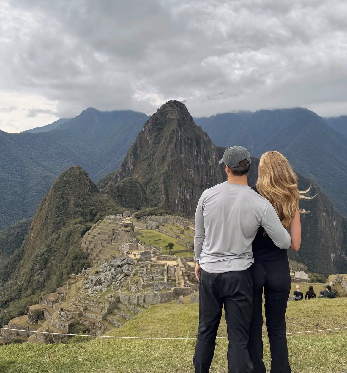 Couple standing arm in arm at the classic Machu Picchu viewpoint