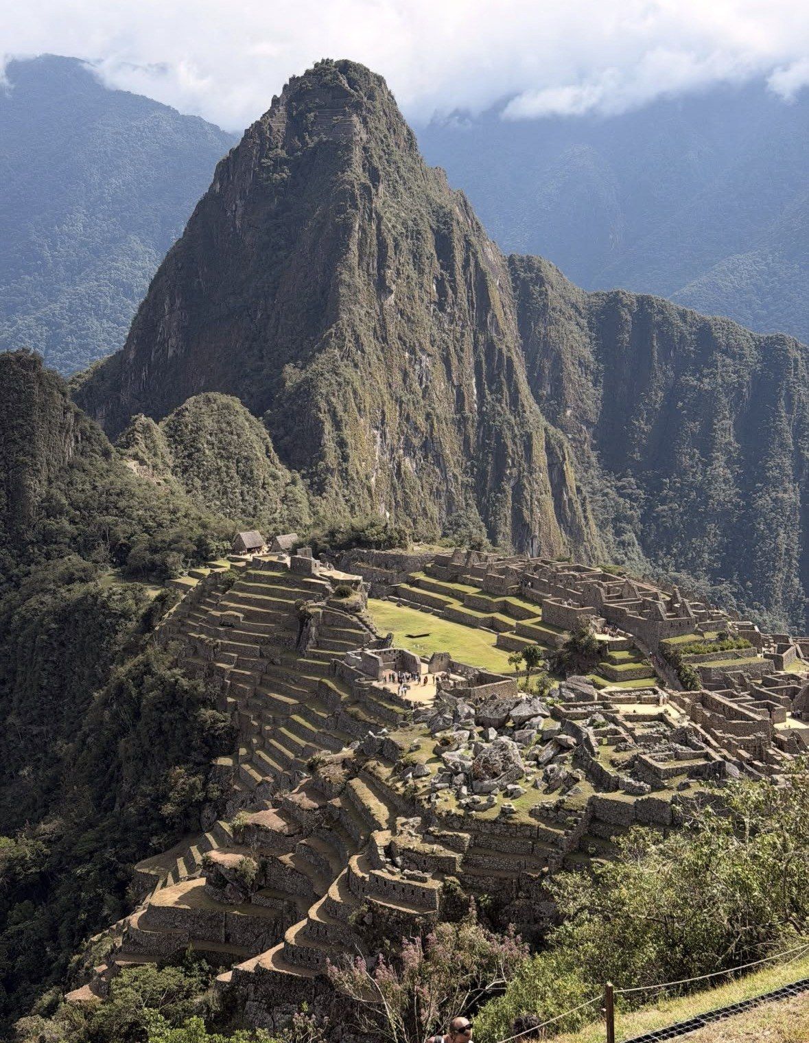 Curved agricultural terraces stepping down below the sunlit Machu Picchu peak